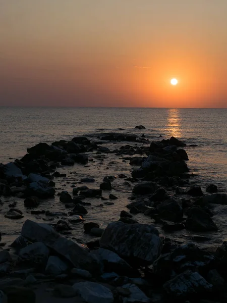 deniz kıyısında gündoğumu, sudan çıkan kayalar arasında