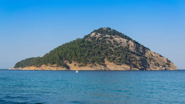 o insula cu copaci içinde marea mediterana si barca pe marea albastr