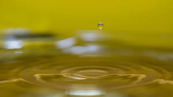 Salpicadura de agua en el fondo colorido con una gota de agua volando —  Fotos de Stock