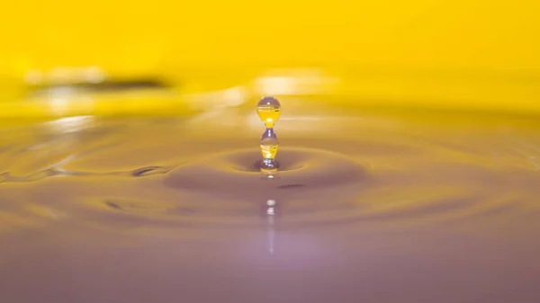 Water splash in colorful background with a drop of water flying — Stock Photo, Image