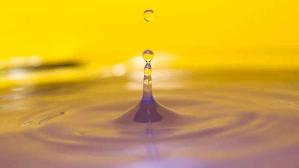 Брызги воды на красочном фоне с каплей летящей воды — стоковое фото