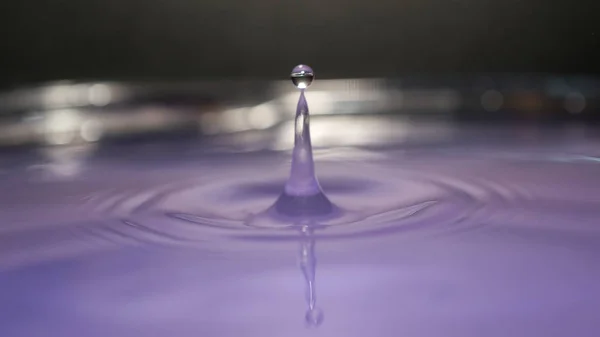 water splash in colorful background with a drop of water flying