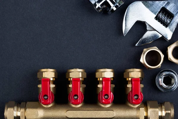 Pirinç manifold valf ve dokulu koyu arka plan üzerinde anahtarı.