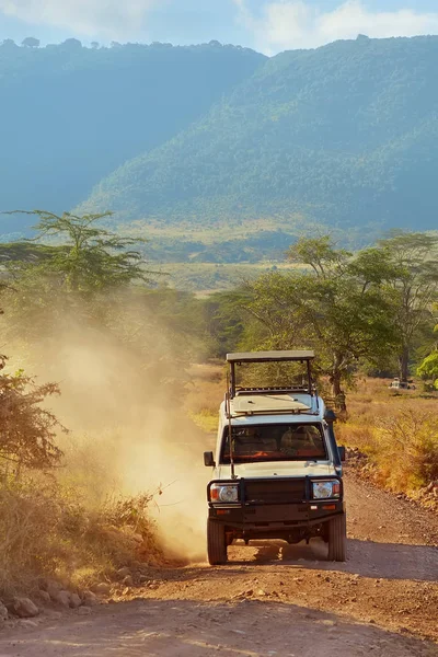 Safari araba Suv 4 x 4 üzerinde off-road savannah Ngorongoro koruma, Tanzanya kirli. Afrika rezerv manzara arka plan üzerine açık çatı 4wd safari cip. Afrika kırsal, dikey banner ortak otomatik                            