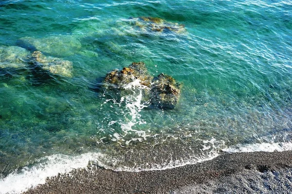 Çakıl taşları, deniz köpüğü, taşlar ve zümrüt rengi temiz deniz suyu ile sahil