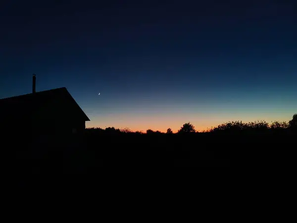Gün batımının muhteşem arka planına sahip ev silueti — Stok fotoğraf
