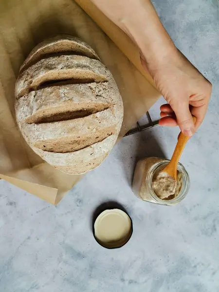 İnsanlar kaşıkla cam kavanozdan çavdar ekmeği topluyor.