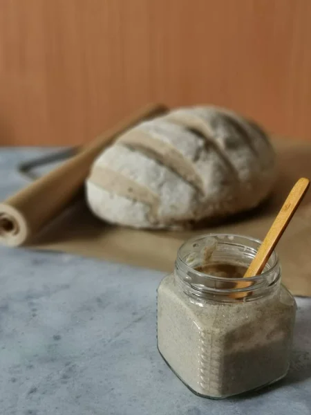 Tarro de vidrio con masa madre y cuchara de madera — Foto de Stock