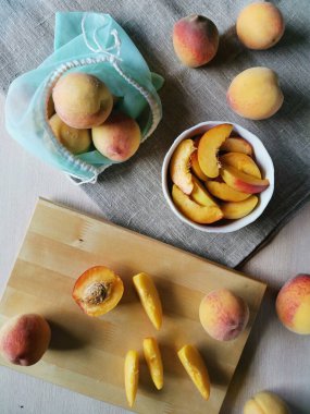 Düz, sulu, şeftali dilimlenmiş bir tabakta, şeftali ve çuval bezinde tekrar kullanılabilir bir çanta.