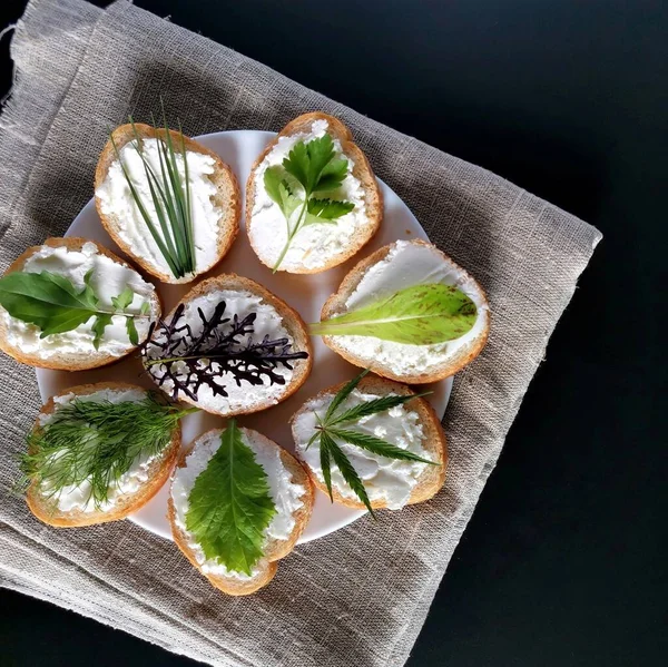 Değişik yeşillikli yararlı sandviçler ve çuval bezinde peynir ve koyu bir arka plan. 