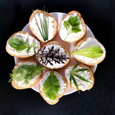 Farklı yeşillikli sandviçler, beyaz tabakta peynir ve koyu bir arka plan. 