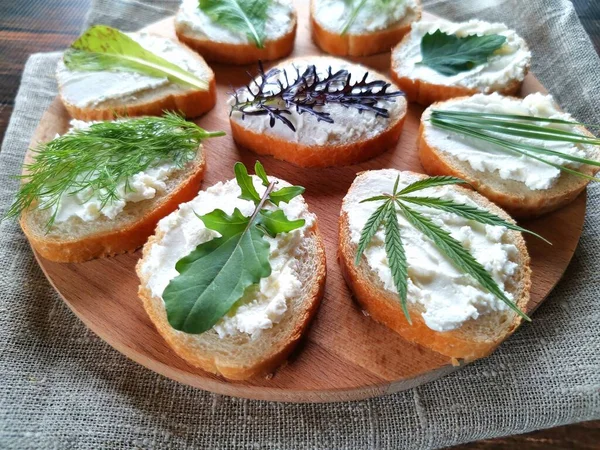 Bagetteki sandviçlerin, peynirin ve tahta ve çuval bezi üzerinde taze yeşilliklerin yakın plan fotoğrafları.
