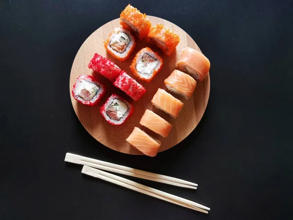 Sushi sobre una plancha de madera sobre fondo negro — Foto de Stock