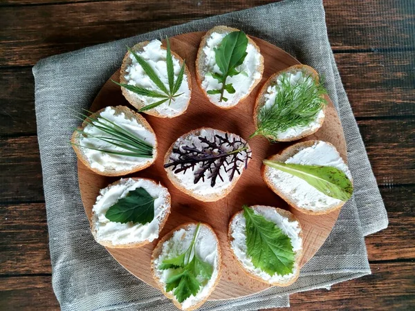 Tahta ve çuval bezi üzerinde baget, peynir ve taze yeşilliklerden lezzetli sandviçler.