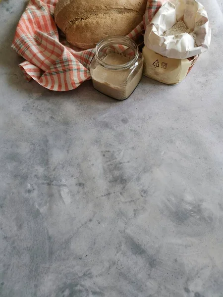 Cam bir kavanozda çavdar ekmeği ve unun yanında gri bir zemin üzerinde