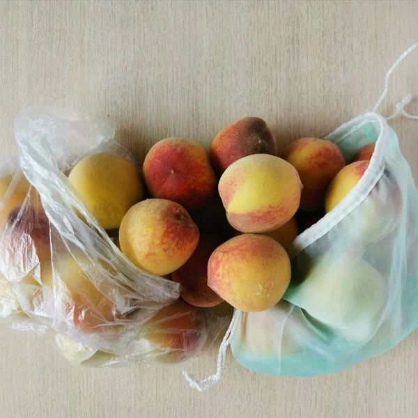 Şeftaliler plastik poşette ve yeniden kullanılabilir çantada.