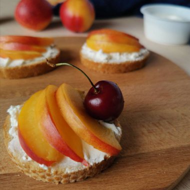  Krem peynirli sandviç, taze nektarin dilimleri ve kirazlı servis tahtası. yakın plan