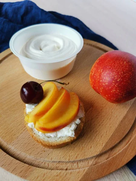 Tahtada sandviçten, nektarinden ve yumuşak peynirden oluşan sağlıklı bir kahvaltı