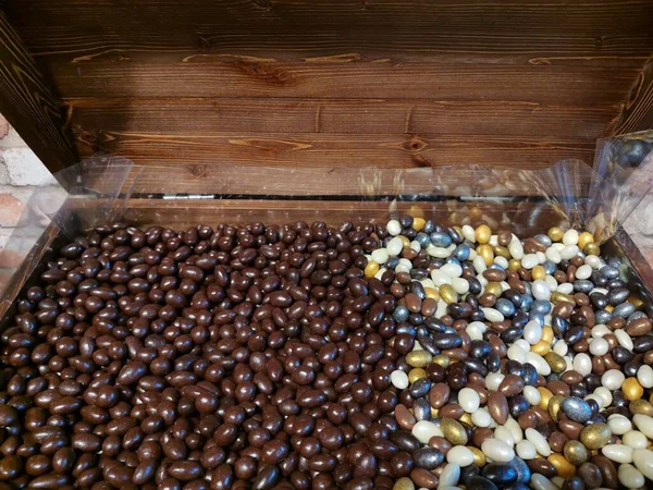 Çikolata kaplı çok renkli fındıklar ahşap bir sandıkta yatıyor.