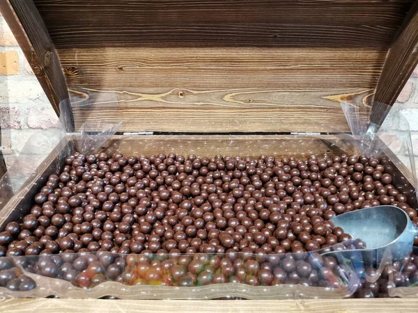 Słodycze orzechy laskowe w czekoladzie mlecznej leżą w klatce piersiowej i scoop — Zdjęcie stockowe