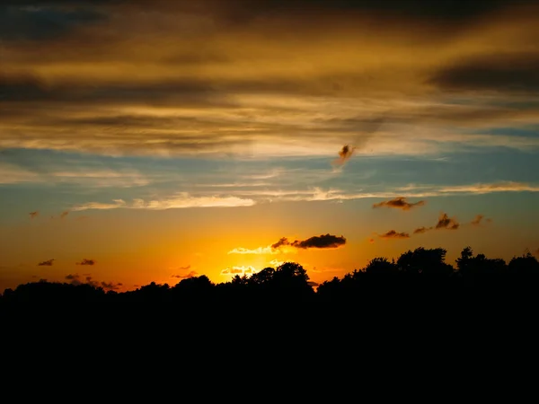 夕阳西下的树木和海边的云彩的轮廓 — 图库照片