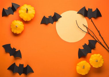 Turuncu arka planda Cadılar Bayramı kağıt süslemeleri. Kara yarasalar, balkabakları, ağaç dalları ve ay. Cadılar Bayramı konsepti Düz yerde, üst tarafta, tepede. Asgari düzeyde. Fotokopi alanı olan Cadılar Bayramı partisi tebrik kartı maketi. 