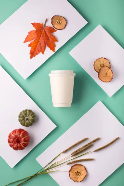 Autumn background for branding and product presentation. Paper cup of coffee on blue table. Take away coffee branding mockup. Autumn holiday concept.