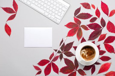 Sonbahar evi kompozisyonu. Klavyeli şık ofis masası. Kırmızı yapraklar yabani üzüm, bir fincan kahve, Gary 'nin arka planında defter. Sonbahar, Şükran Günü konsepti. Düz konum, üst görünüm, kopyalama alanı