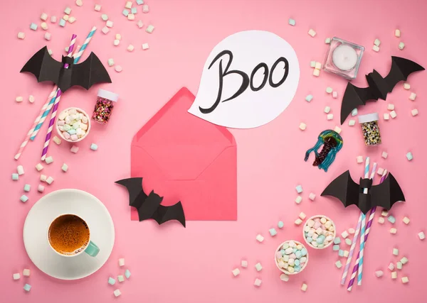 Happy Halloween holiday concept. Halloween decorations, black bats, candy on paper pink background. Halloween party greeting card mockup with copy space. Flat lay, top view, overhead.