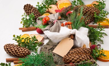 Ahşap masa üzerinde yeşil dallar, kozalaklar, portakallar ve elmalarla bezenmiş keten kumaşlara sarılmış zarif kırsal hediyeler. Düz yatıyordu. Basit eko plastik olmadan sunar. Sıfır kayıp Noel.