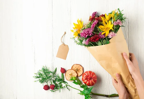 女性の手 白木の背景にカボチャの黄色とオレンジの花の秋の花束 感謝祭の日や他の休日のための秋の概念 コピースペース — ストック写真