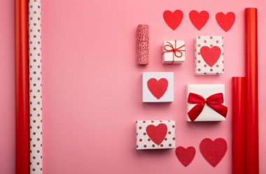 Noel, sevgililer günü, düğün ya da diğer tatil kompozisyonları. El yapımı paketlenmiş hediye kutuları, kırmızı kalpler ve pembe kağıt arkaplanda yazı için fotokopi alanı olan diy araçları. Düz yatış, üst görünüm.