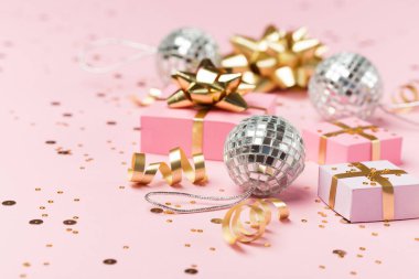 Noel kompozisyonu. Altın ve gümüş süslemeler, ayna disko topları, pastel pembe kağıt arka planda hediyeler. Noel, kış, yeni yıl konsepti. Seçici odak, boşluğu kopyala.