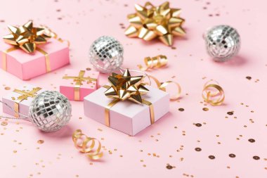 Noel kompozisyonu. Altın ve gümüş süslemeler, ayna disko topları, pastel pembe kağıt arka planda hediyeler. Noel, kış, yeni yıl konsepti. Seçici odak, boşluğu kopyala.