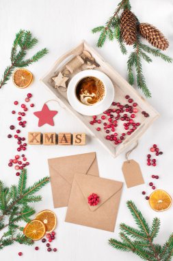 Sıfır Noel konsepti. Doğal Xmas dekorasyonu, boş zarflar, bir fincan kahve, çam kozalakları ve beyaz ahşap arka planda dallar. Düz yerde, üst tarafta. Tatil metni için boş alan.