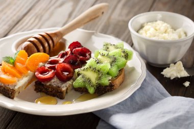 Taze meyve, kayısı, kivi, tuzlu feta peyniri ve bal karışımı, ahşap bir arka planda, seçici bir odak noktası.