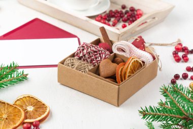 Sıfır Noel konsepti. El yapımı Noel hediyesi. Plastik, kızılcık, kozalak ve dallar olmadan paketleniyor. Çevre dostu bir hediye. Kış zamanı, beyaz ahşap zemin.