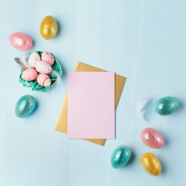 Mavi pastel arka planda altın, gümüş renginde Paskalya yumurtaları ve metin için yer var. Düz konum resim kompozisyonu, üst görünüm. Paskalya dekorasyonu, folyo minimalist yumurta tasarımı, modern tasarım şablonu.