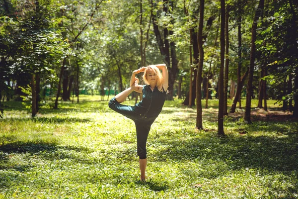 Natarajasana. Yoga asanas in nature. Yoga poses everyday. Practicing young woman. Yoga in the park