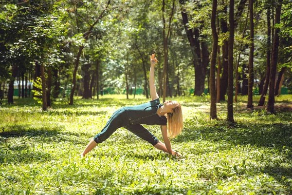 Utthita trikonasana. Yoga asanas in nature. Yoga poses everyday. Practicing young woman. Yoga in the park