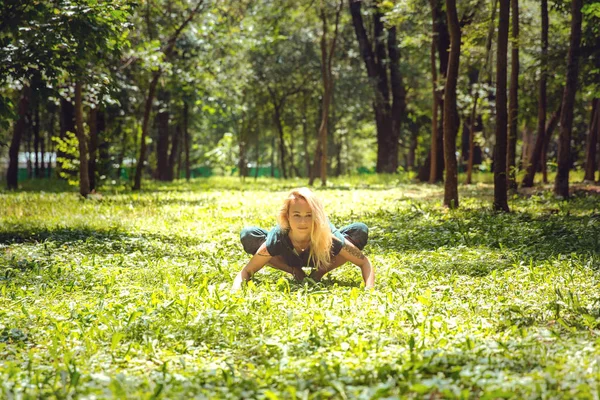 Malasana. Yoga asanas in nature. Yoga poses everyday. Practicing young woman. Yoga in the park