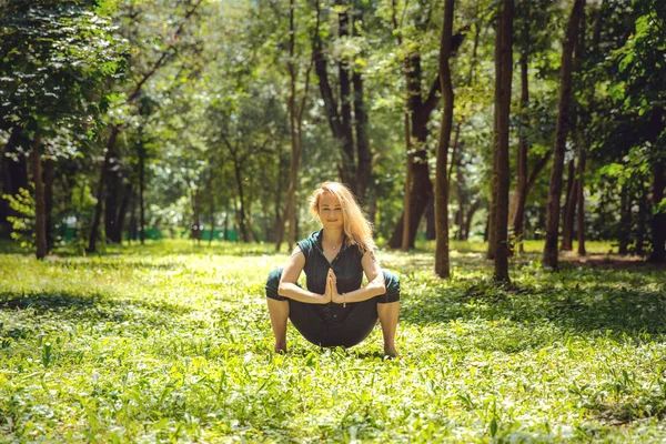 Kagasana. Yoga asanas in nature. Yoga poses everyday. Practicing young woman. Yoga in the park