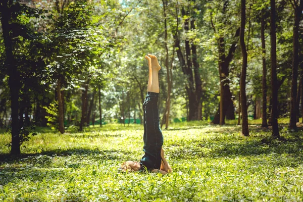 Salamba Sarvangasana. Yoga asanas in nature. Yoga poses everyday. Practicing young woman. Yoga in the park