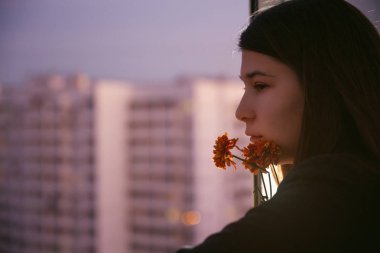 Genç doğal güzellik uzun saçlı kız çiçekli balkon. Bahar. İyi akşamlar. Yüksek katlı alanı. Portre. Estetik