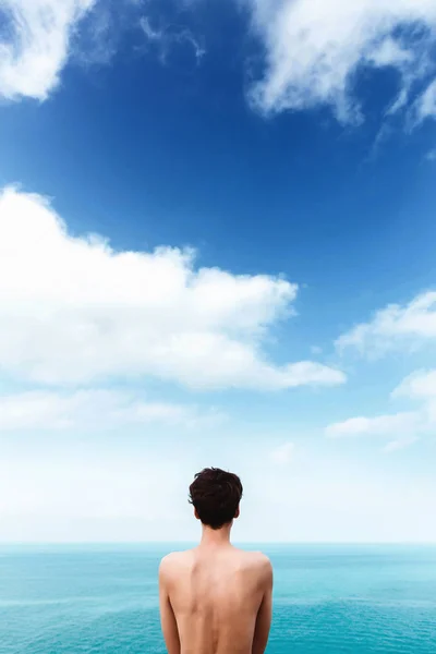 Chica delgada con una hermosa espalda desnuda está de pie en el mar. Cielo azul con nubes. Unidad con la naturaleza. libertad. La vida — Foto de Stock