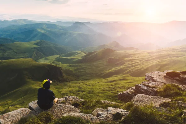 Travel man tourist sitting alone on the edge mountains over green valley adventure lifestyle extreme vacations green landscape Freedom — Stock Photo, Image