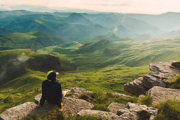 Reisemann Tourist sitzt allein am Rande Berge über grünem Tal Abenteuer Lebensstil Extremurlaub grüne Landschaft Freiheit — Stockfoto