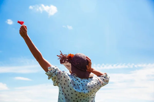 Mujer joven con sombrero disfrutando de la hora de verano sosteniendo una flor roja Viajes Estilo de vida emociones felices vacaciones al aire libre cielo azul Sonrisa chica turista caminando día soleado — Foto de Stock
