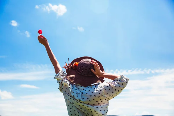 Mujer joven con sombrero disfrutando de la hora de verano sosteniendo una flor roja Viajes Estilo de vida emociones felices vacaciones al aire libre cielo azul Sonrisa chica turista caminando día soleado — Foto de Stock
