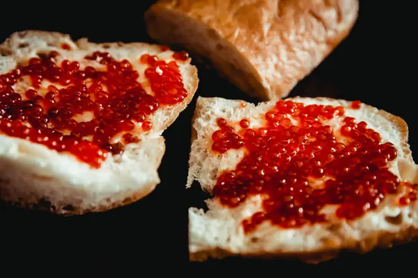 Sandwiches de pan blanco fresco con mantequilla y caviar rojo en un plato. Fondo oscuro — Foto de Stock